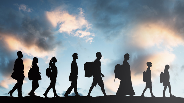 Silhouettes of people with luggage against cloudy sky. Photo by Andrey Popov from iStock.