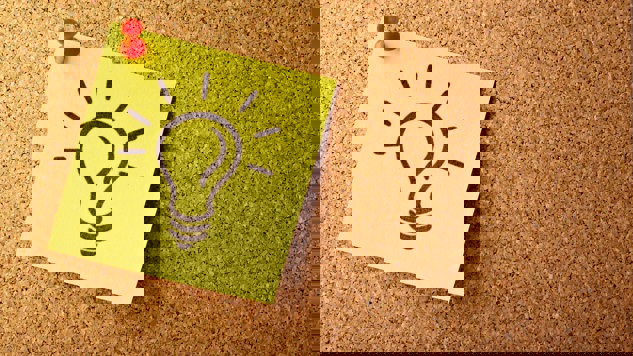 Gul post-it-lapp med en tecknad glödlampa på en anslagstavla i kork.