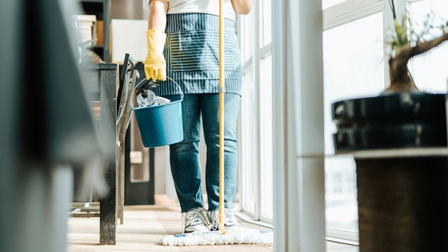 A man holding a mop and a cleaning bucket