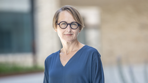 Porträttbild på Annika som står framför en tegelbyggnad. Bild: Arbetsförmedlingen.