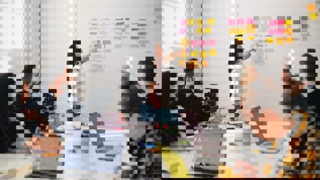 En kvinna som placerar post it-lappar på en whiteboard-tavla. Bild: Unsplash.