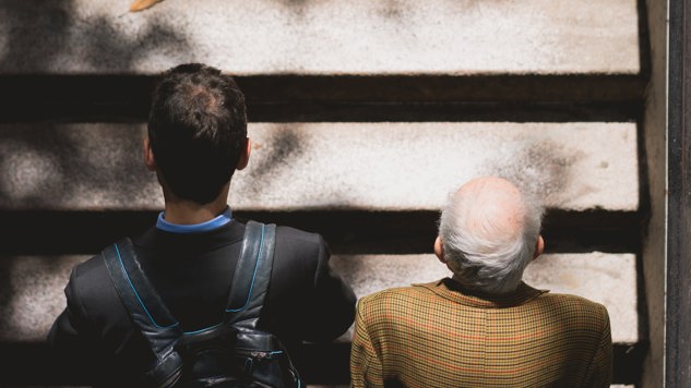 En ung man och en äldre man promenerar tillsammans uppför en trappa. Bild: Unsplash.