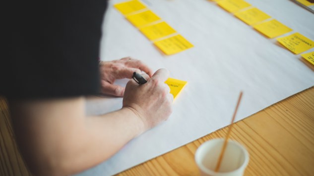 A person who is writing on yellow post-it notes. Picture: Unsplash.