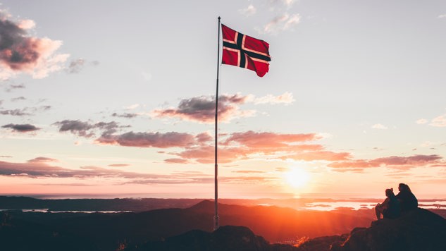 A Norway flag standing on a cliff. Picture: Unsplash.