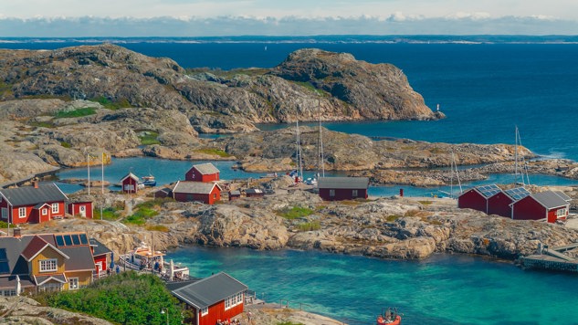 Cliffs and small red cottages by the water in the archipelago. Photo by Ferhat Deniz Fors Unsplash