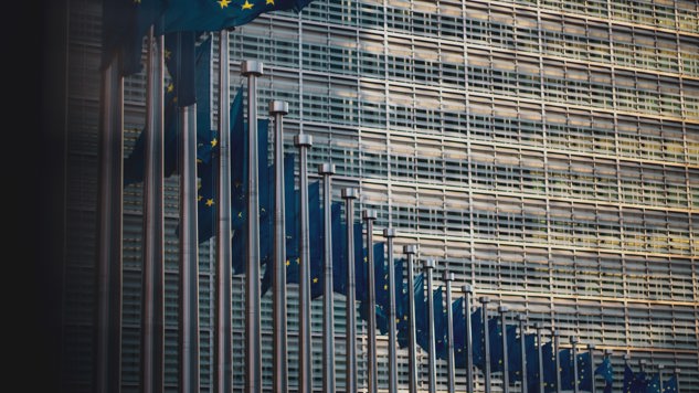 EU-flaggor framför kommissionsbyggnaden. Foto av Christian Lue från Unsplah.