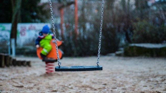 A playground with a swing and a child in the background. Picture: Unsplash.