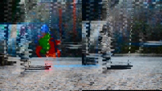 A playground with a swing and a child in the background. Picture: Unsplash.