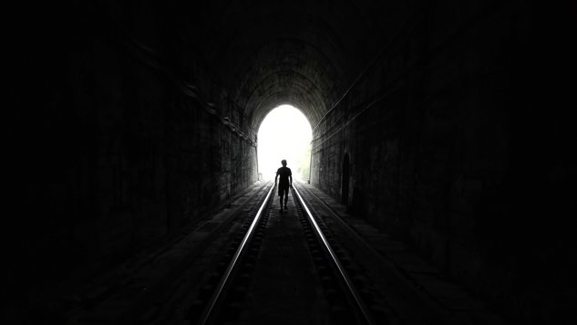En person går i en mörk tunnel. Bild: Unsplash.