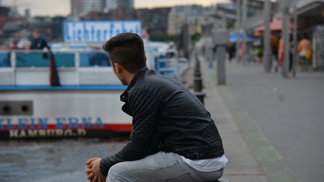 En ung man som sitter vid en strandpromenad. Bild: Pixabay.
