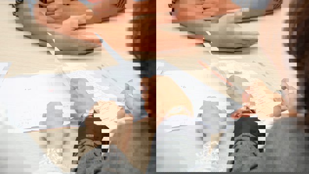 Tre personer sitter runt ett bord med papper framför sig. Bild: Unsplash.